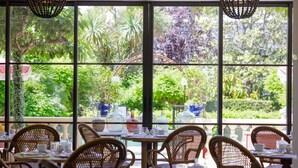 A restaurant with wicker chairs and tables, large windows with a view of lush greenery. - Hôtel La Villa Sainte Valérie Adults Only (Antibes)