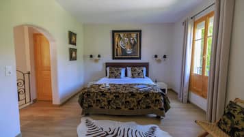 A bedroom with a bed, a zebra rug, a tiger painting, and a door.