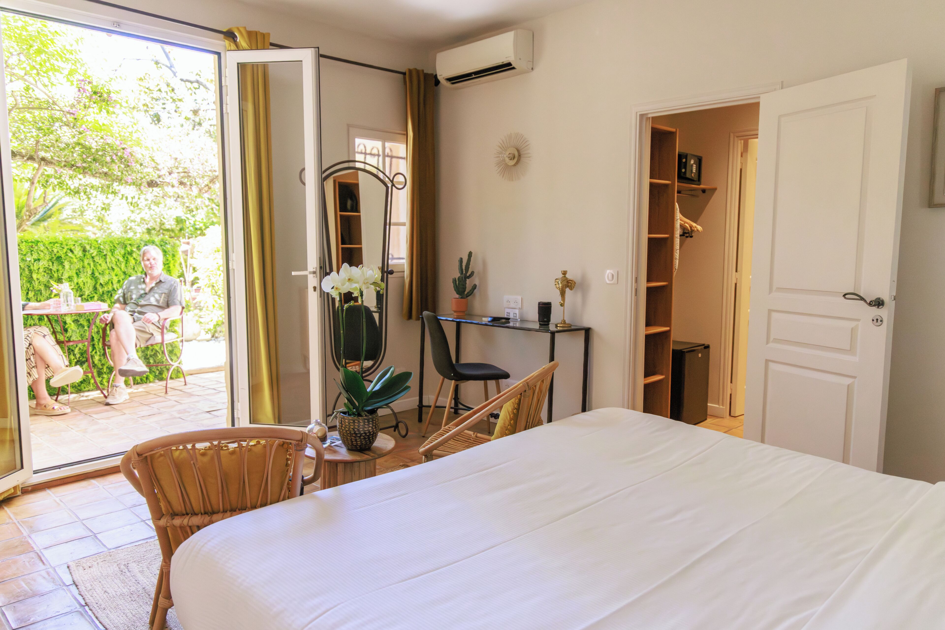A bedroom with a bed, a desk, a chair, a potted plant, and a wardrobe.