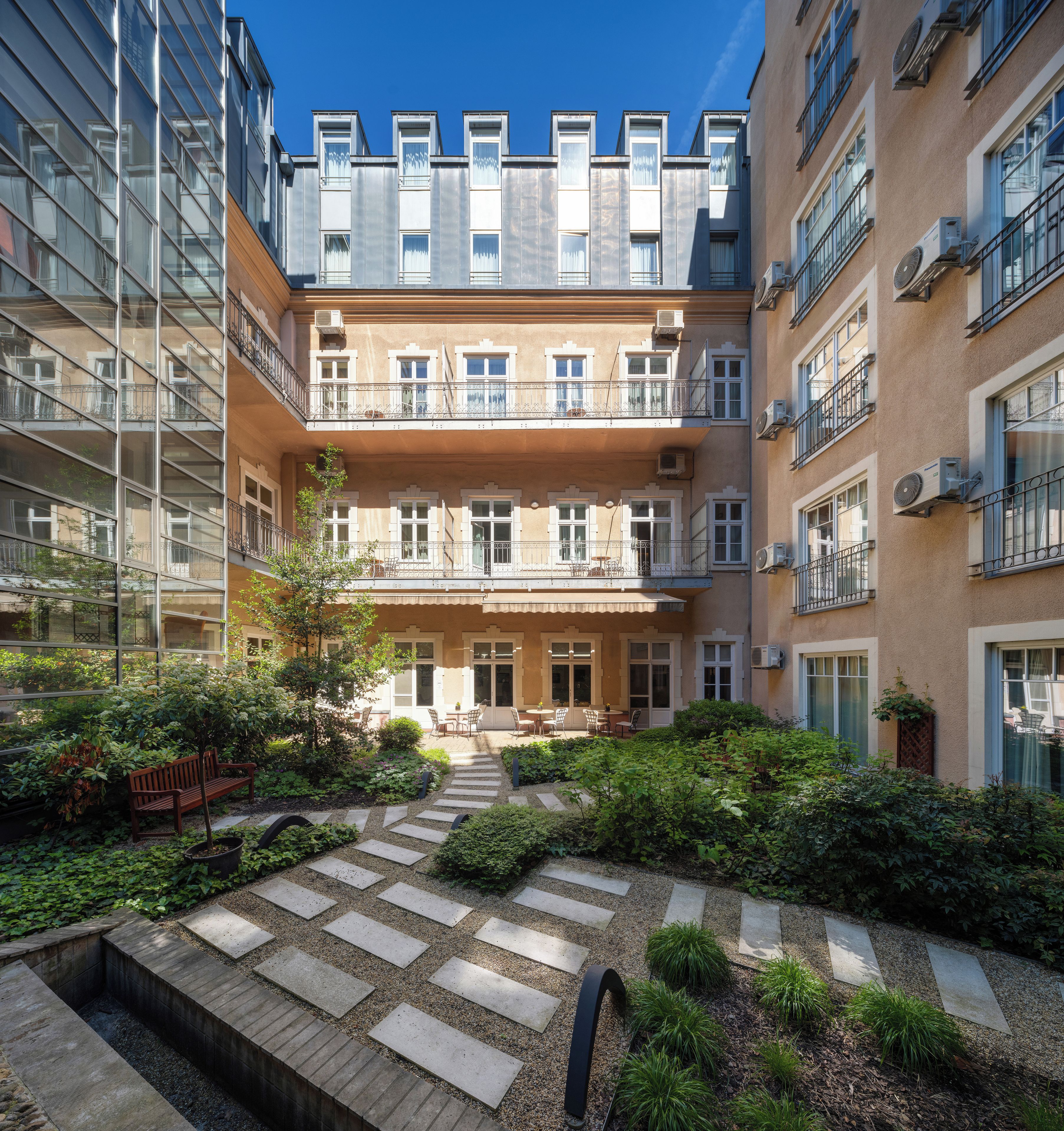 Een binnentuin met een centraal gelegen zitgedeelte, omringd door gebouwen met balkons en airconditioners.