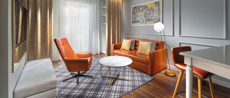 A modern living room with a sofa, two armchairs, a coffee table, and a dining area.