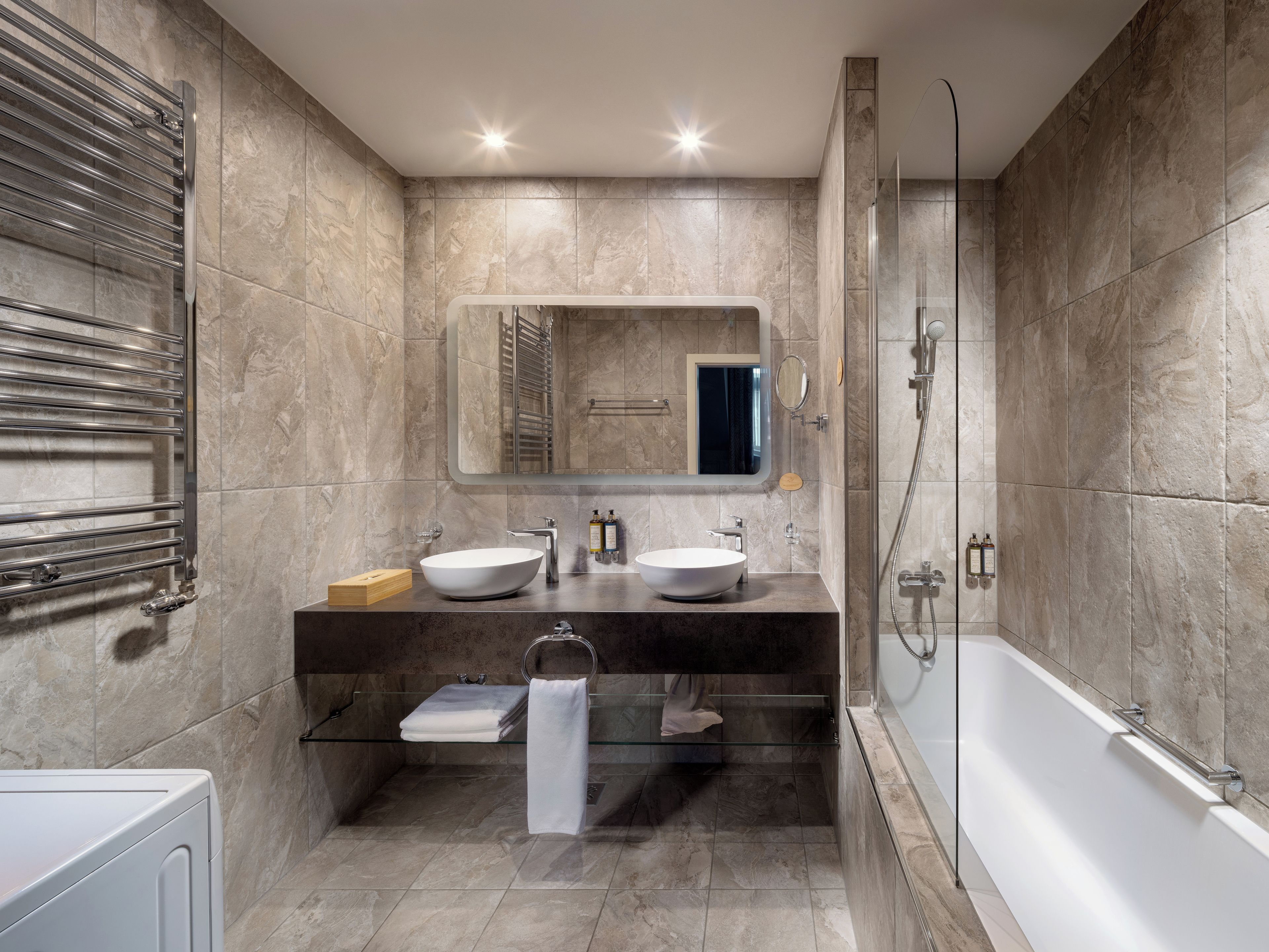 A modern bathroom with a glass-enclosed shower, a double sink vanity, and a built-in towel rack.