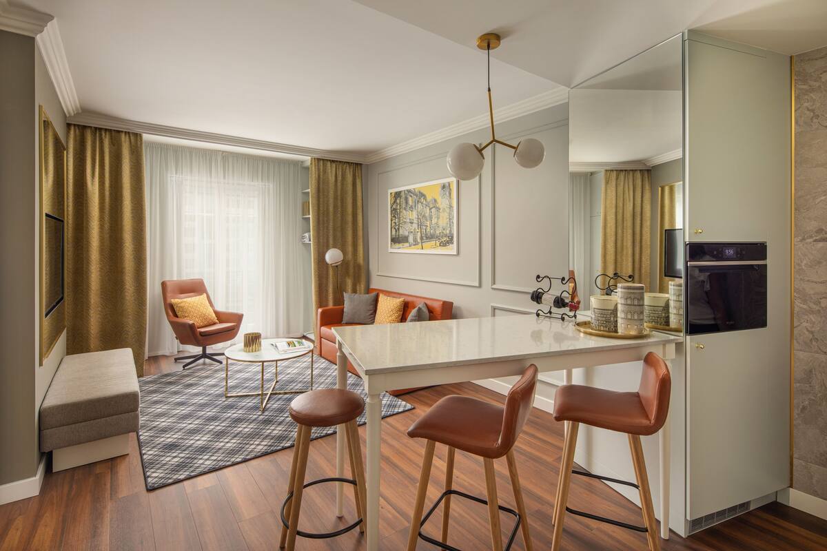 Une chambre d’hôtel moderne comprenant un coin repas, un canapé, une table basse et un coin cuisine.