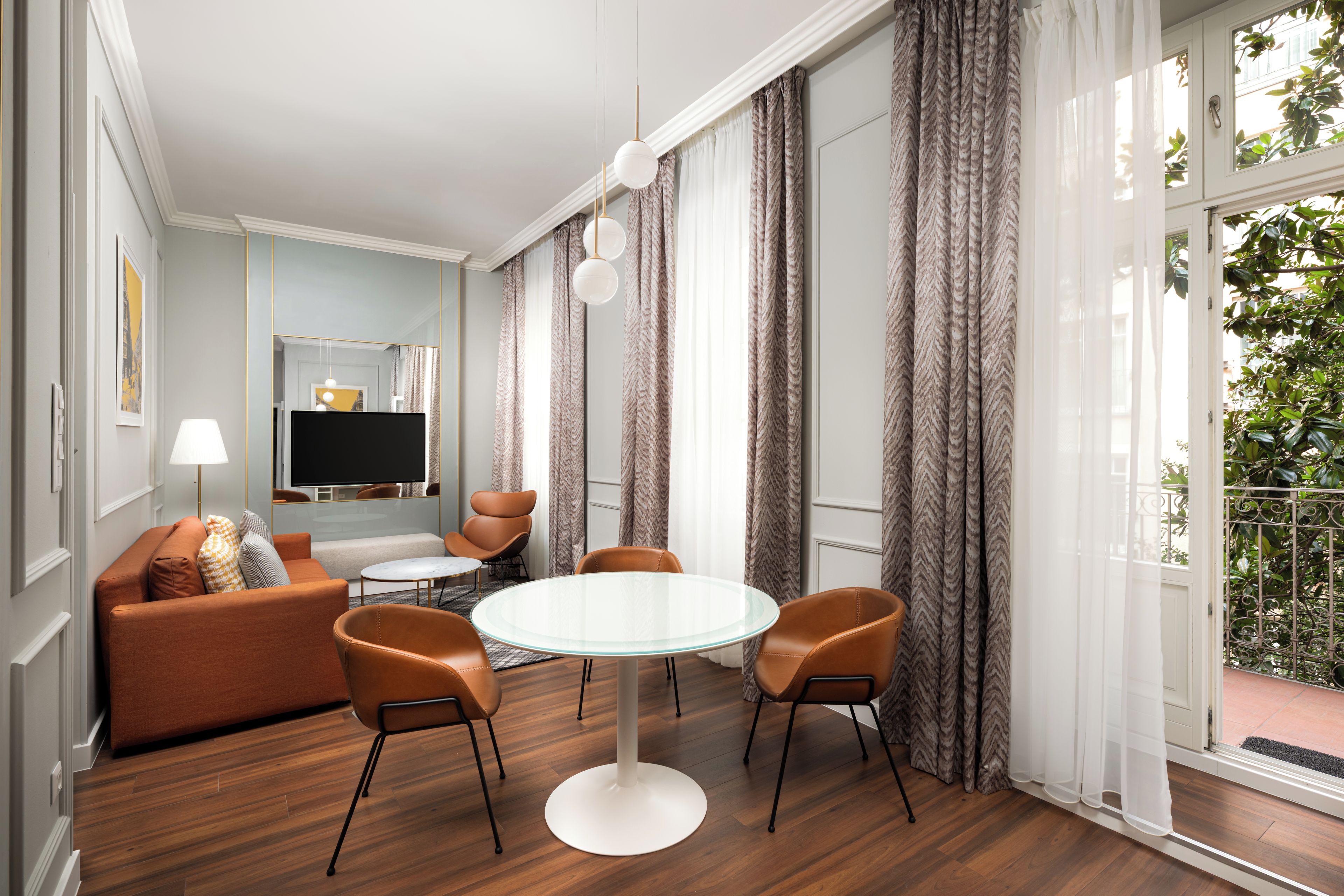 Una sala moderna con un sofá, sillas, una mesa de vidrio y un televisor.