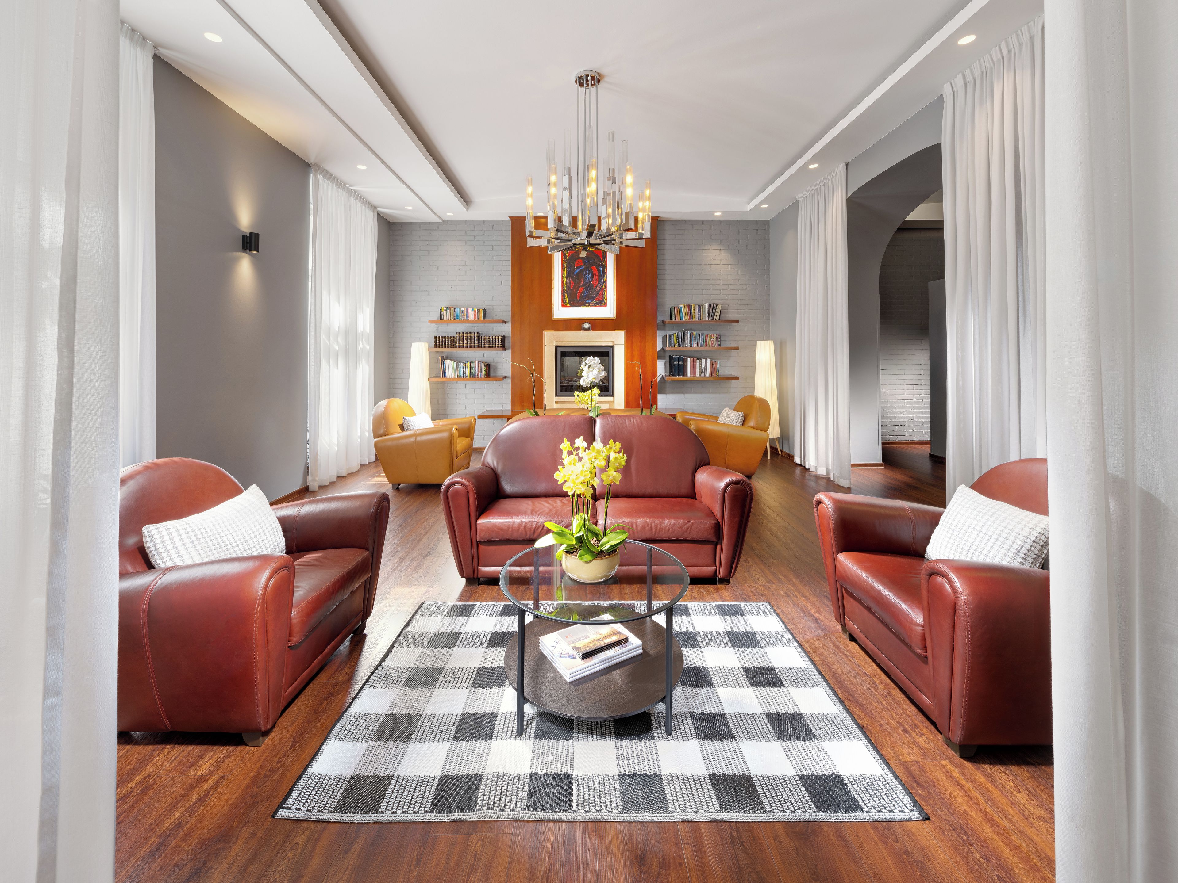 A modern living room with leather sofas, a glass coffee table, and a checkered rug.