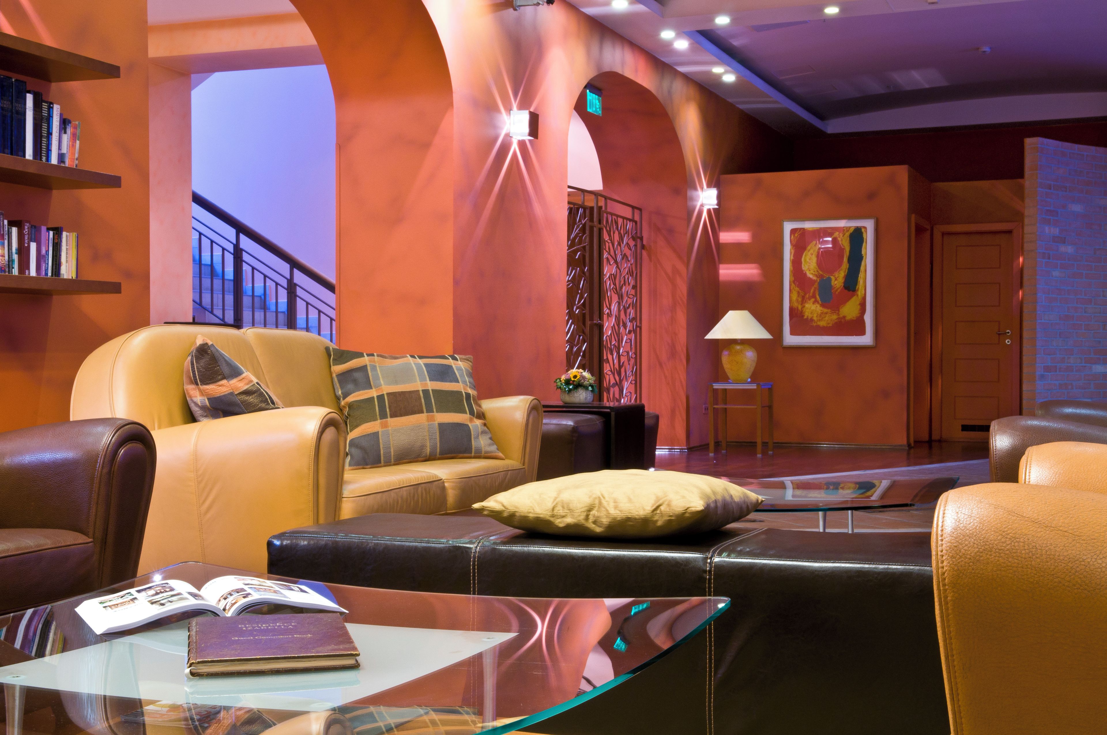 A modern lounge area with leather seating, a glass coffee table, and a bookshelf.