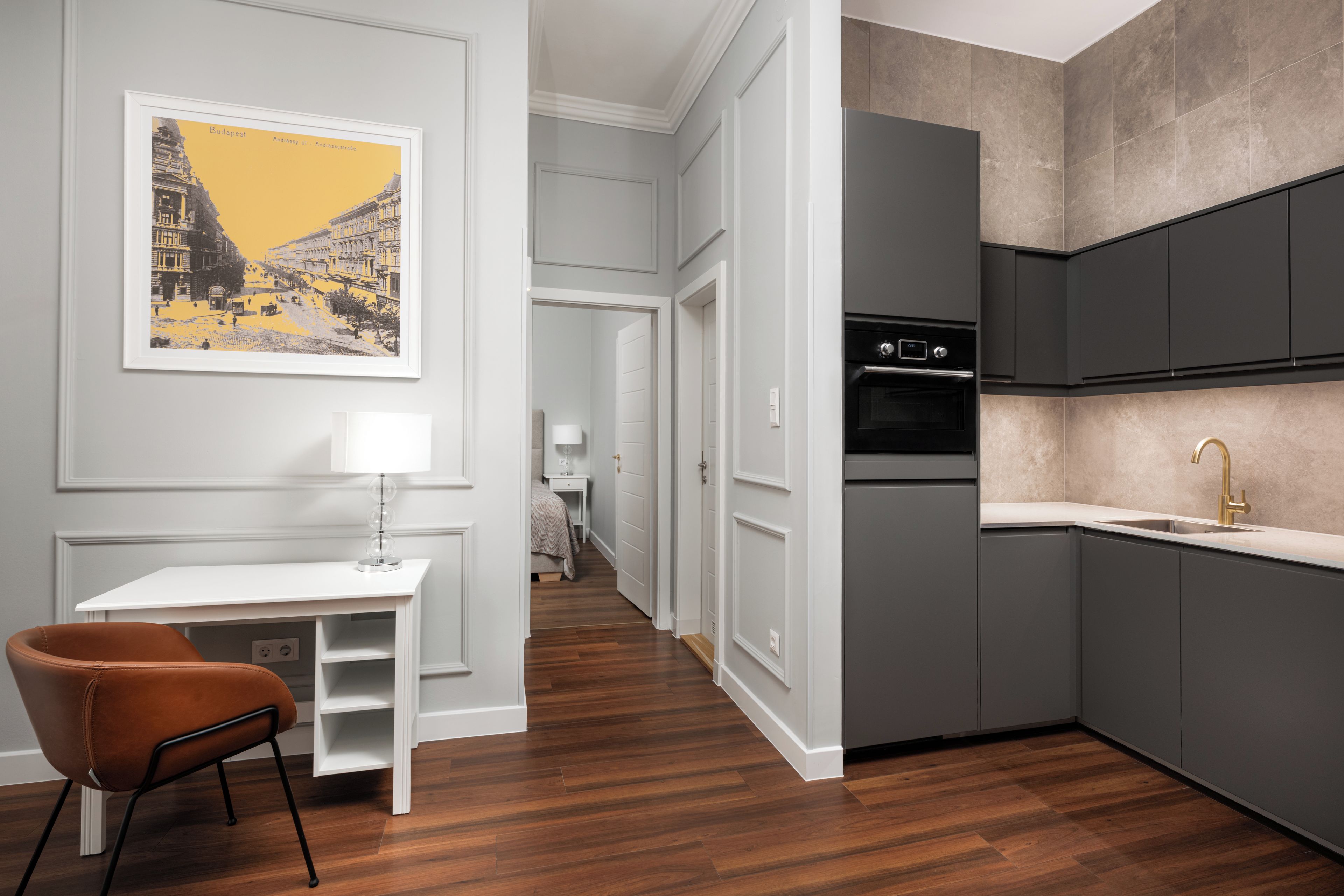 A modern kitchen with grey cabinets, a stainless steel oven, and a gold faucet.