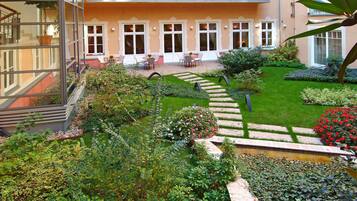 Une cour avec un jardin, des sièges extérieurs et un bâtiment doté de nombreuses fenêtres et de balcons.