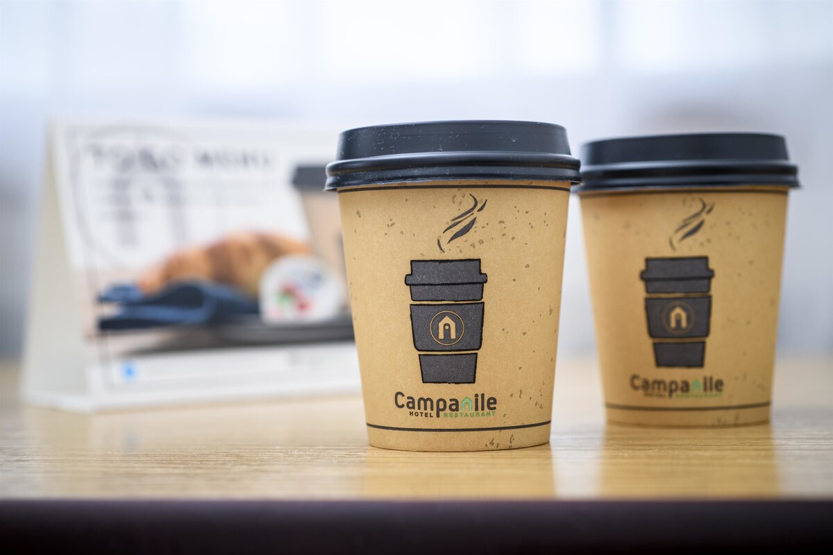 Deux tasses à café, ornées d’un logo et d’une inscription, posées sur une surface en bois.