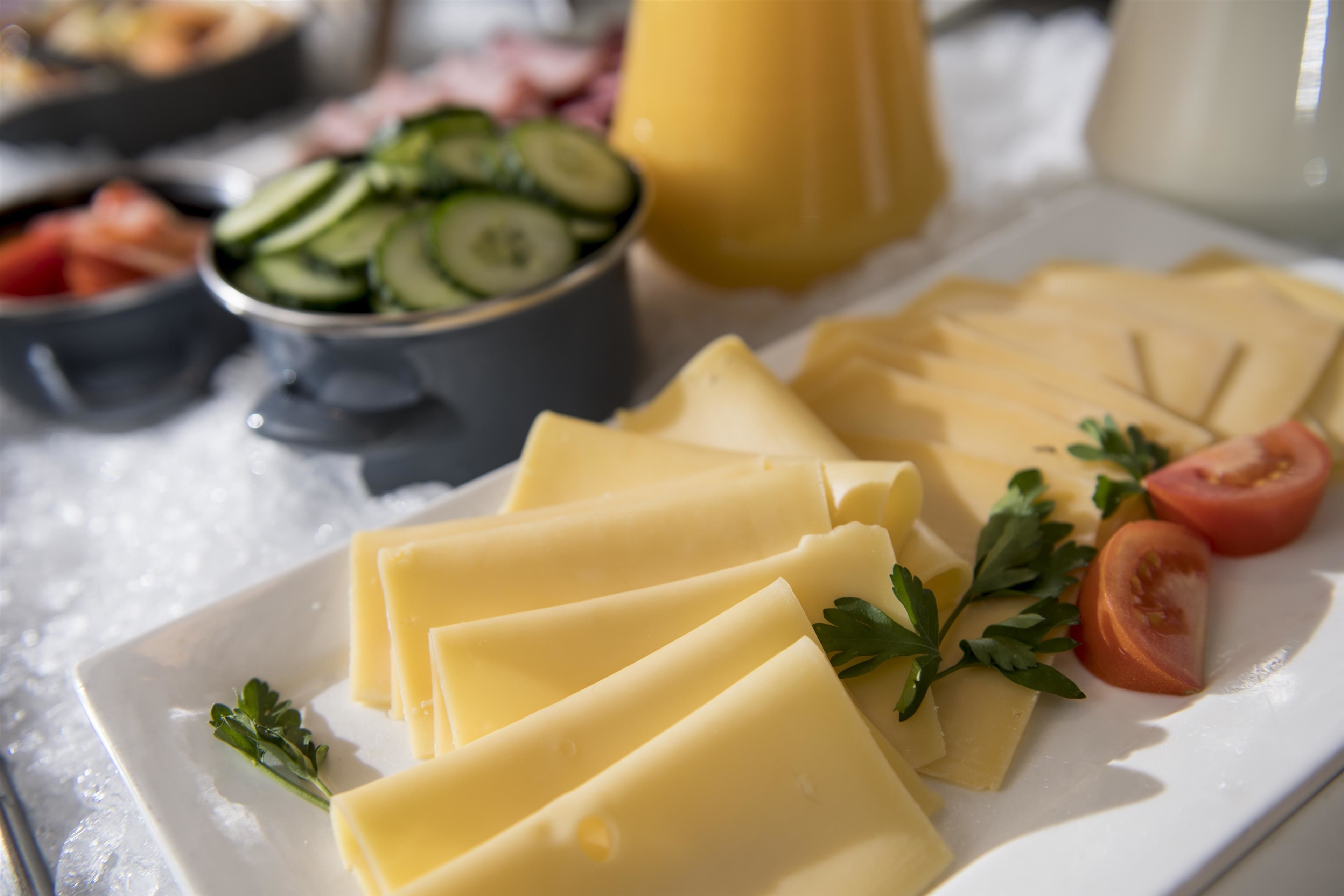 A plate with cheese, tomatoes, and cucumbers on a bed of ice.
