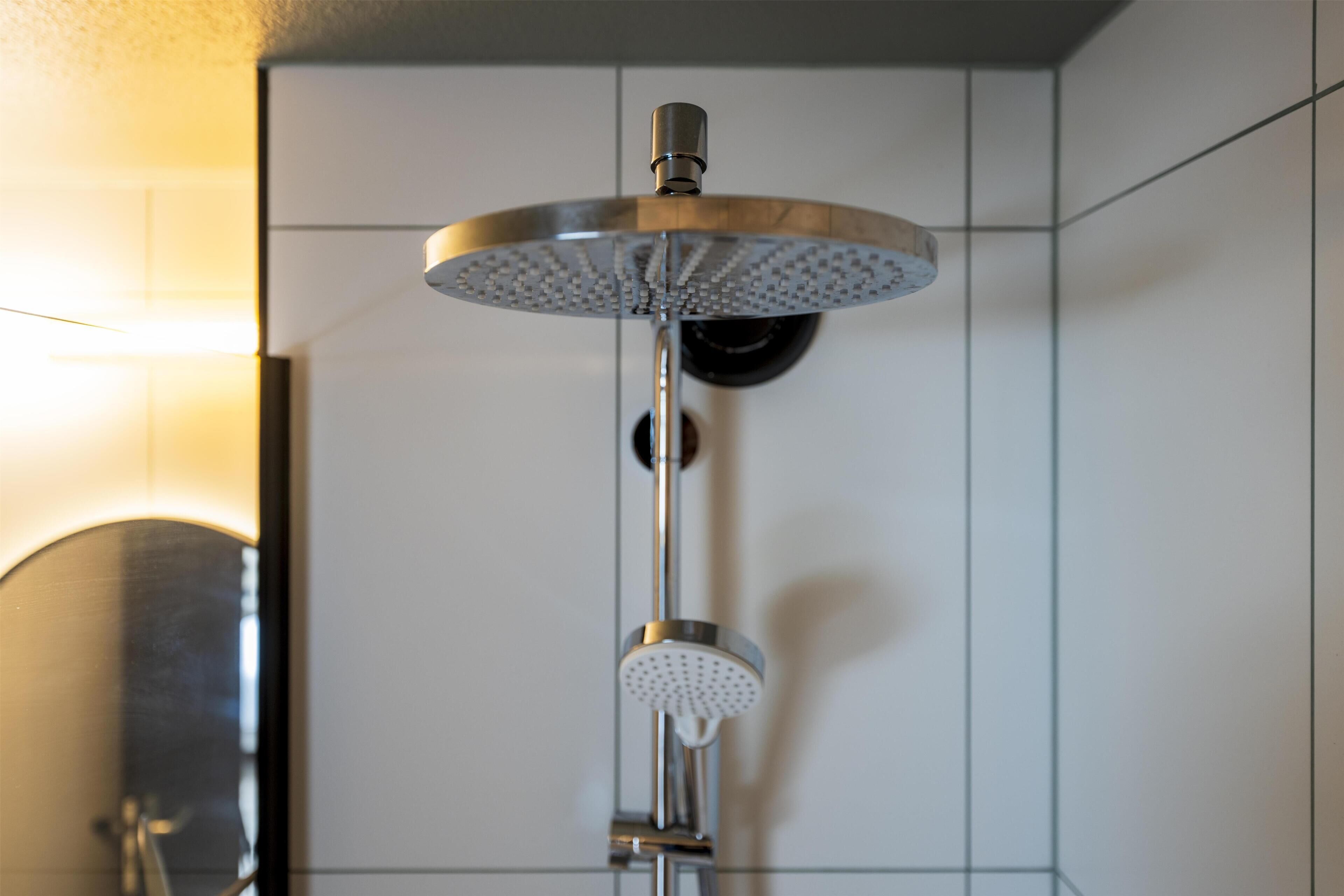 Un cabezal de ducha moderno con diseño circular, fijado a una pared con azulejos.