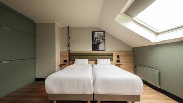 A bedroom with two beds, a skylight, a radiator, and a framed picture on the wall.