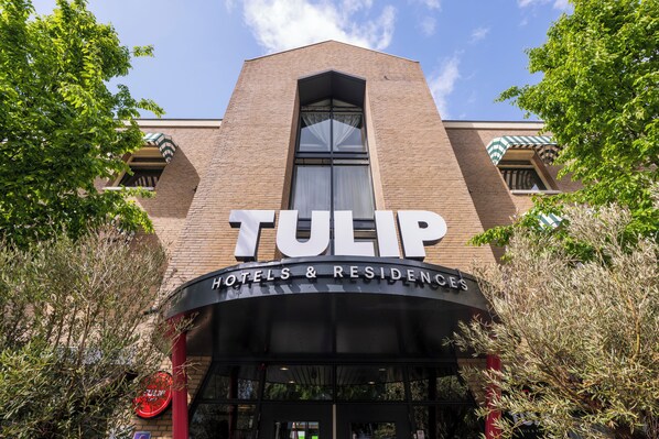 Ett hotell som heter ”TULIP” med en tydlig skylt, en fasad av tegel och stora fönster.