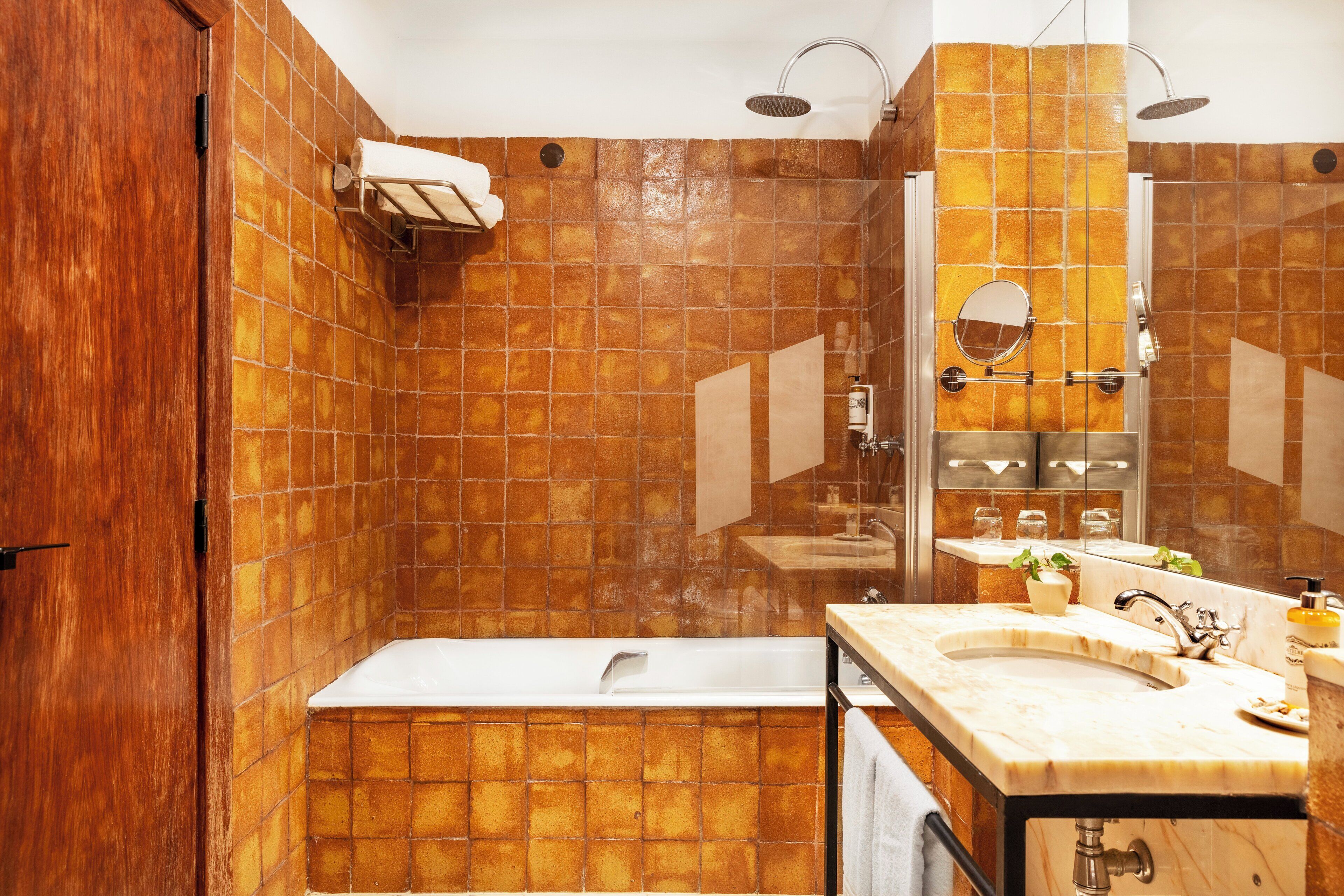 A bathroom with a bathtub, a sink with a mirror, and a shower area.