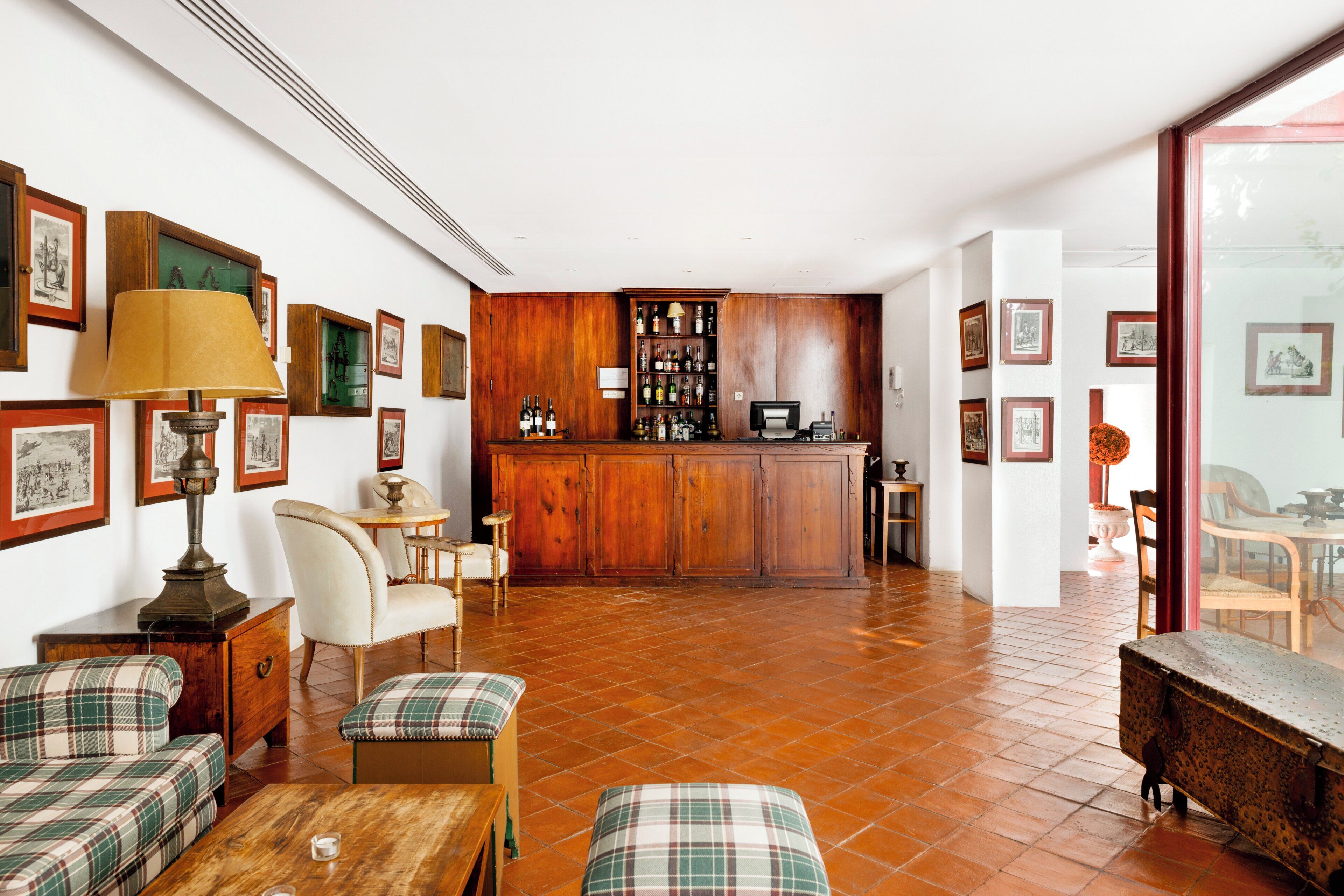 Amplia sala de estar con piso de madera, zona de bar con gabinete para licores y comedor con mesa y sillas.