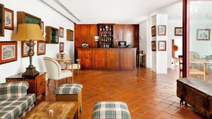 A spacious living area with a wooden floor, a bar area with a liquor cabinet, and a dining area with a table and chairs. - Pousada Convento de Vila Viçosa - Historic Hotel (Vila Vicosa)