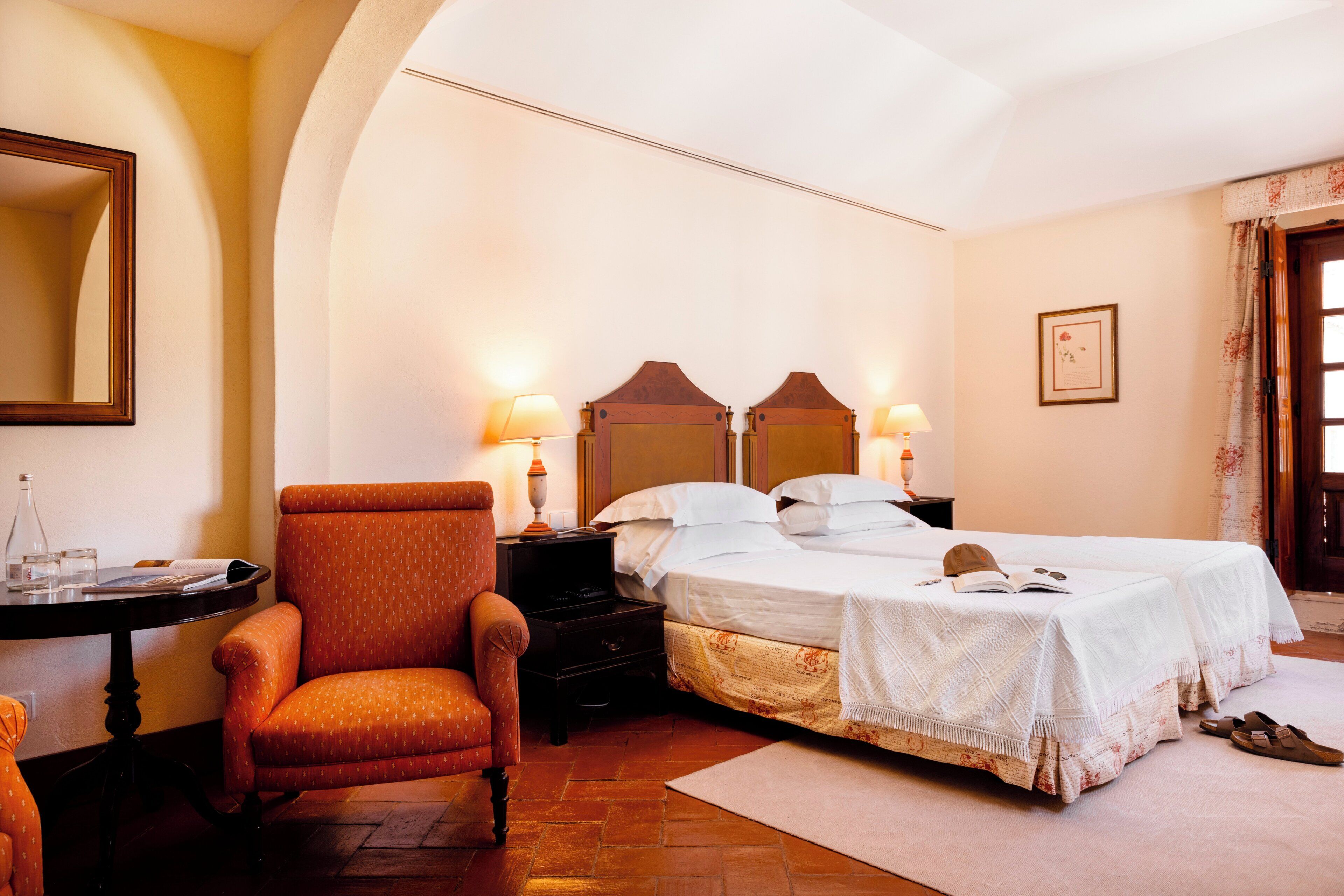A hotel room with a bed, two bedside tables, a chair, a desk, and a mirror.