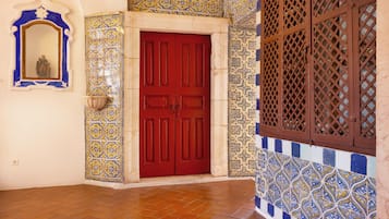 Una puerta roja con un diseño de azulejos decorativos en las paredes y un ventanal de celosía.