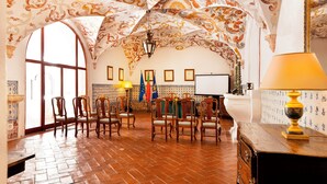 A room with a high arched ceiling, wooden chairs, a table with a lamp, and a flag on the wall. - Pousada Convento de Vila Viçosa - Historic Hotel (Vila Vicosa)