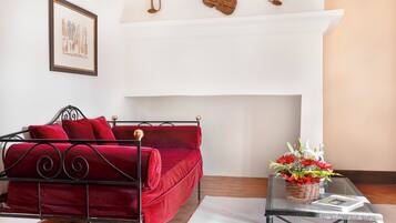 A room with a red sofa, a glass coffee table, a fireplace, and a framed picture on the wall.