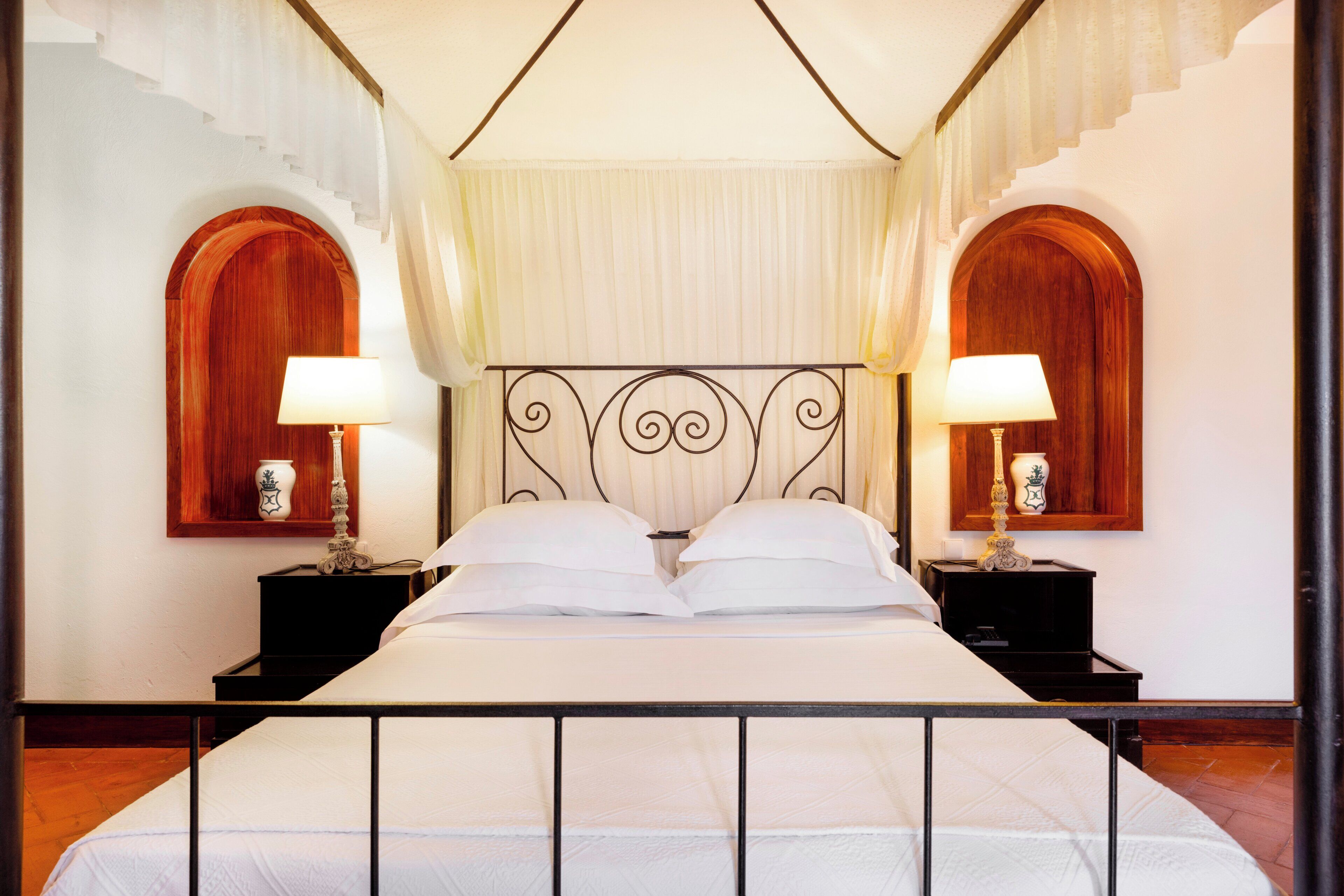 Une chambre d’hôtel comprenant un lit, deux tables de chevet, deux lampes et une tête de lit décorative.