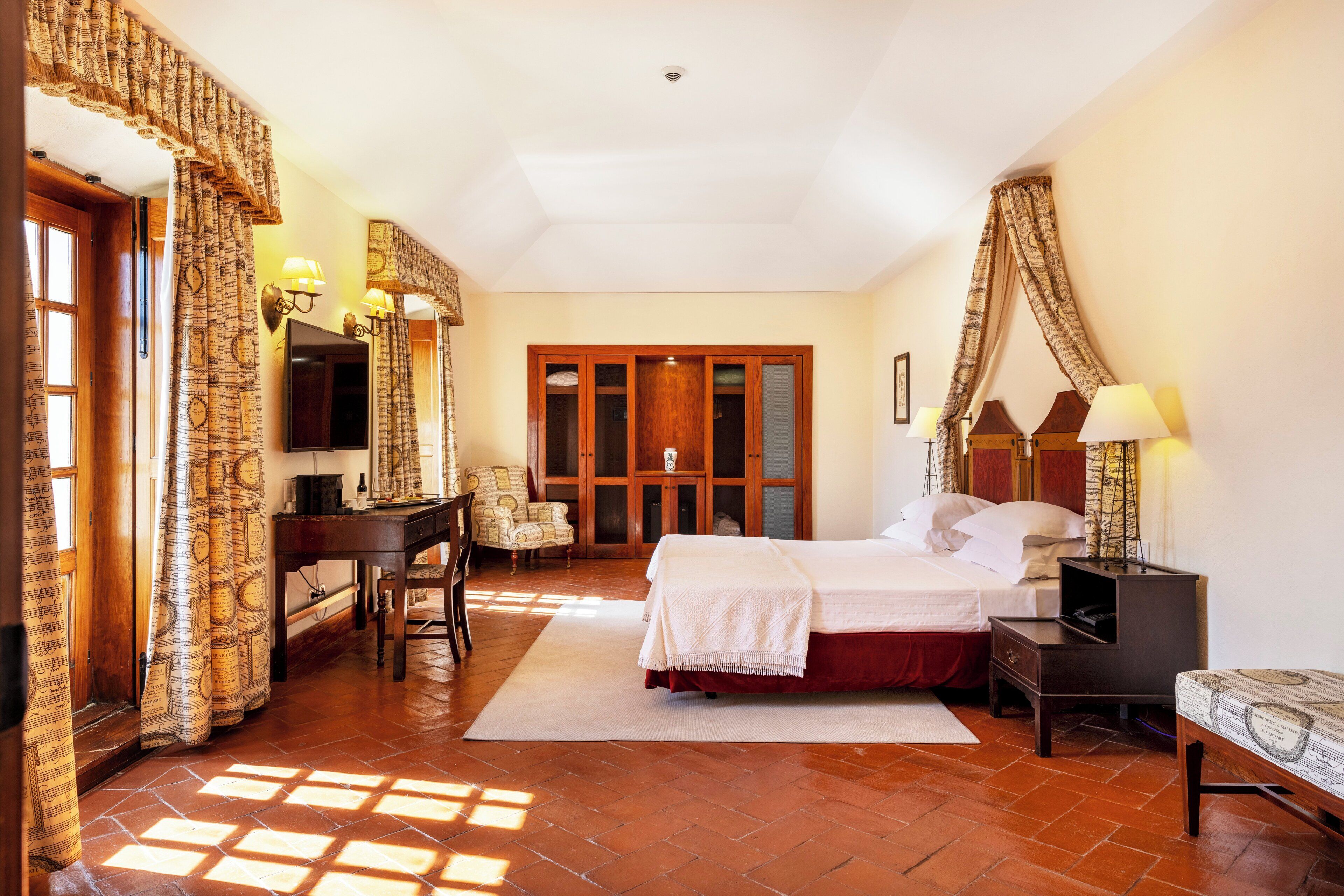 Habitación de hotel con cama, escritorio, silla y televisor.