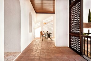 A covered outdoor patio with a table and chairs, a wooden ceiling, and a lattice door.