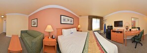 A hotel room with a bed, a desk, a chair, a TV, and a lamp. - Inn By The SFO (South San Francisco)