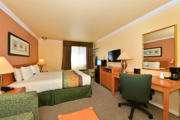 Une chambre d’hôtel équipée d’un lit, d’un bureau, d’une chaise, d’une télévision et d’un miroir.
