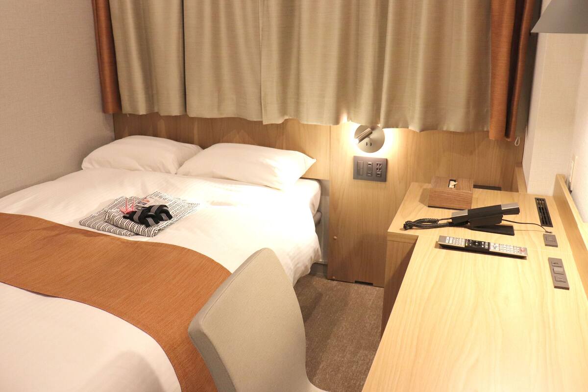A hotel room with a bed, a desk, and a lamp.
