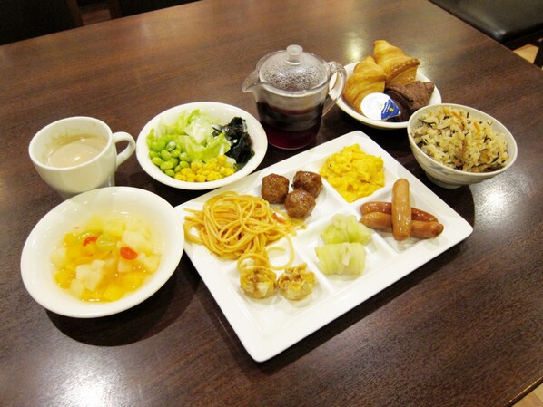 A table with various dishes including pasta, sausages, and a cup of tea. - Tokyo Inn (Tokyo)