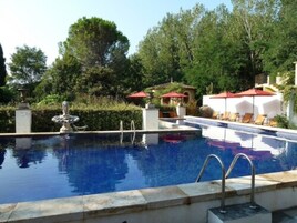 Una piscina al aire libre de temporada, sombrillas
