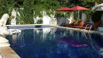 Una piscina al aire libre de temporada, sombrillas