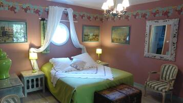 Un dormitorio con cama, dos lámparas de noche, mesita de noche, una silla, un espejo y una ventana con cortinas.