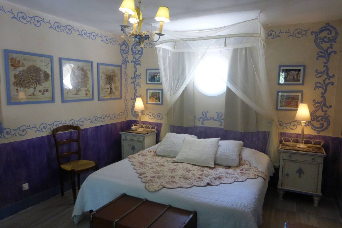 Une chambre à coucher comprenant un lit, deux tables de chevet, une chaise, un lit à baldaquin et des éléments de décoration murale.