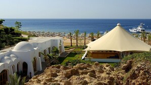 Un resort costero con edificios blancos, una playa y un muelle para barcos.