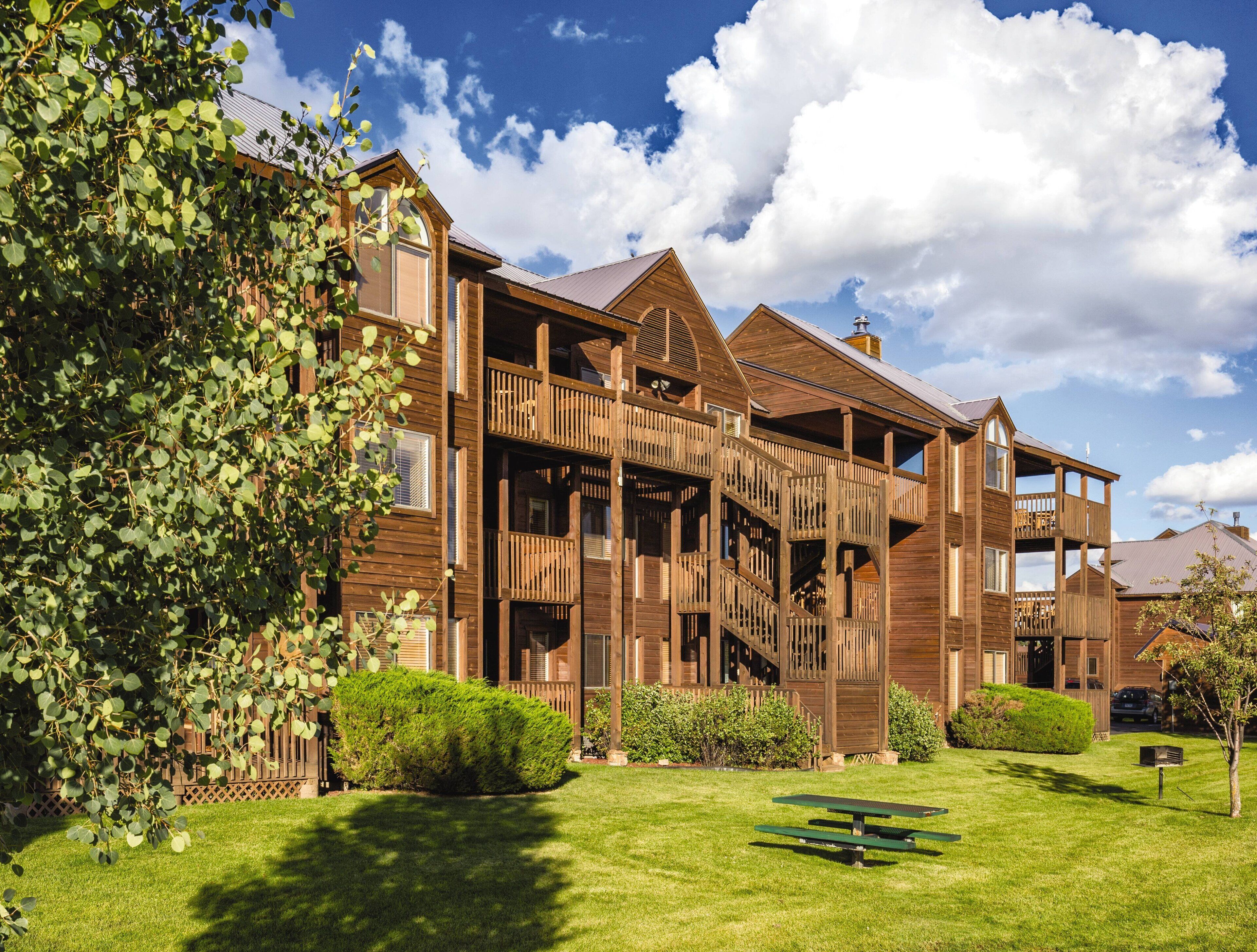 A large wooden building with multiple balconies and a well-maintained lawn.