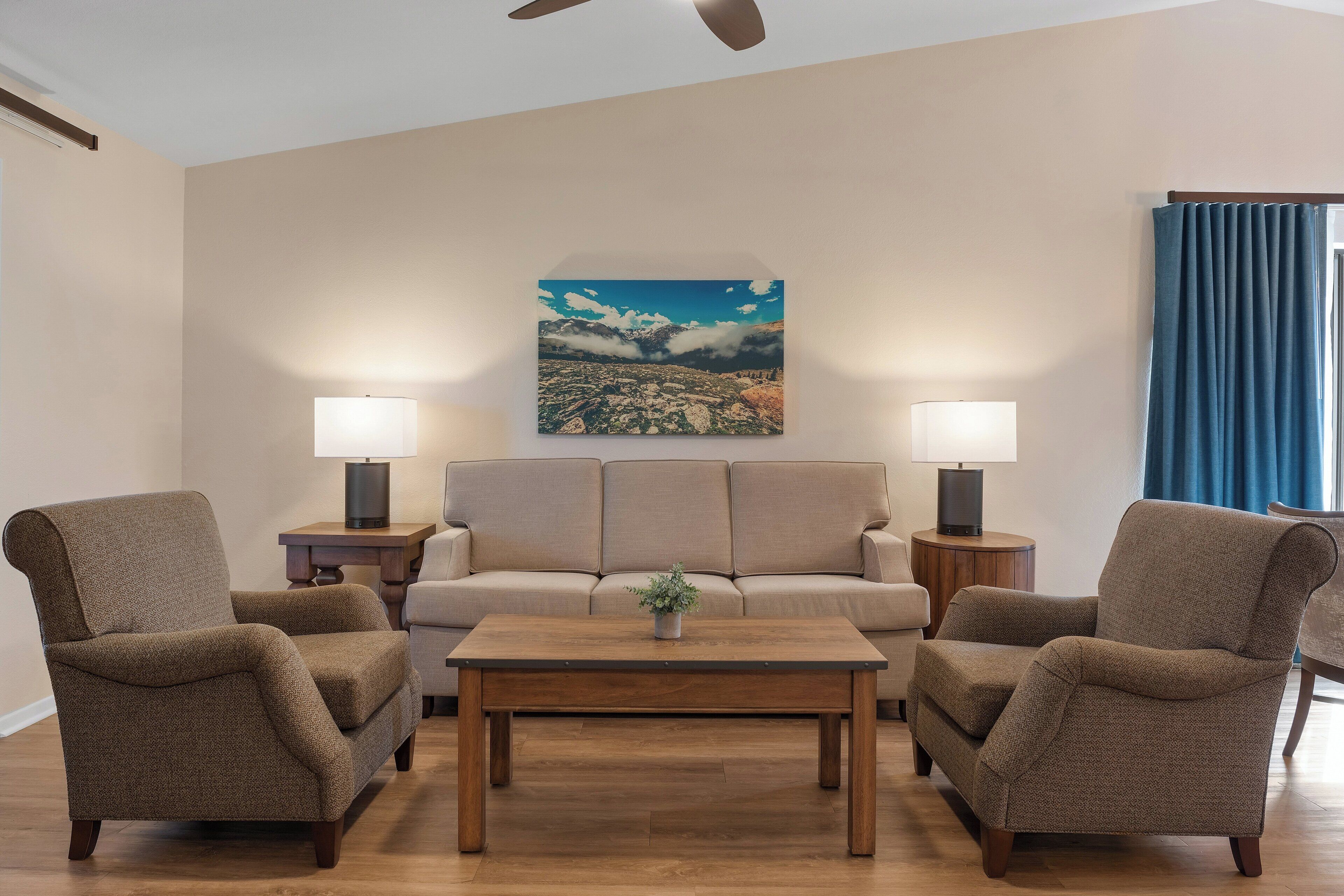Een woonkamer met een bank, twee fauteuils, een salontafel en een schilderij aan de muur.