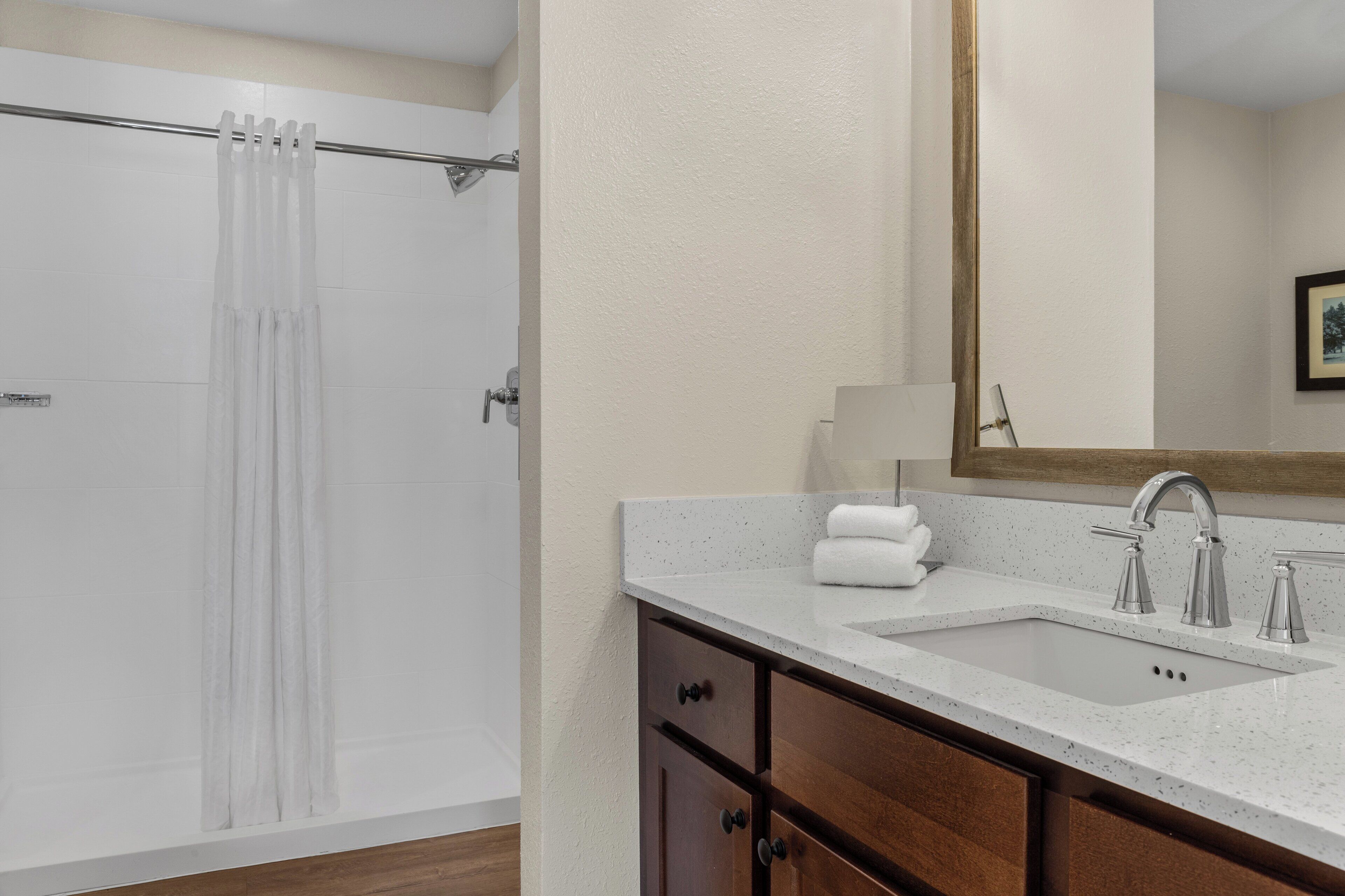 A bathroom with a shower, a sink, and a mirror.