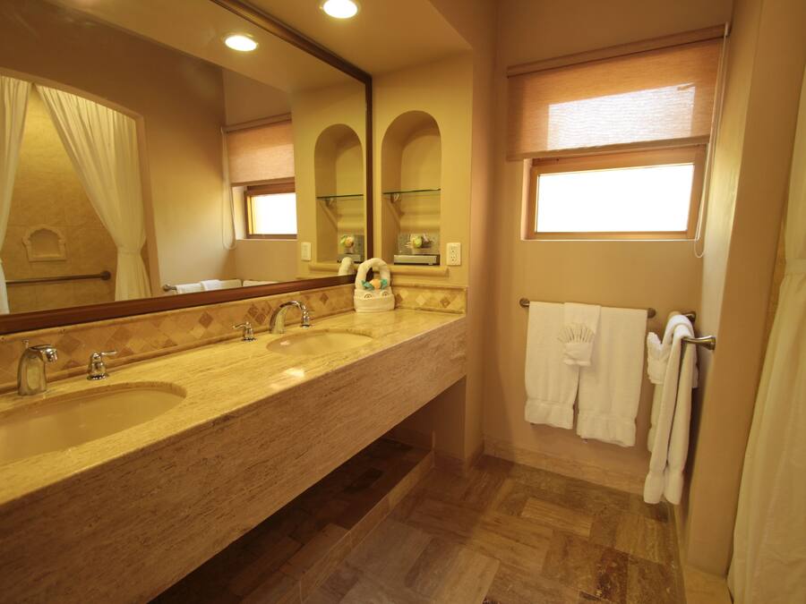 A bathroom with a double sink, a large mirror, a towel rack, and a window with a view.