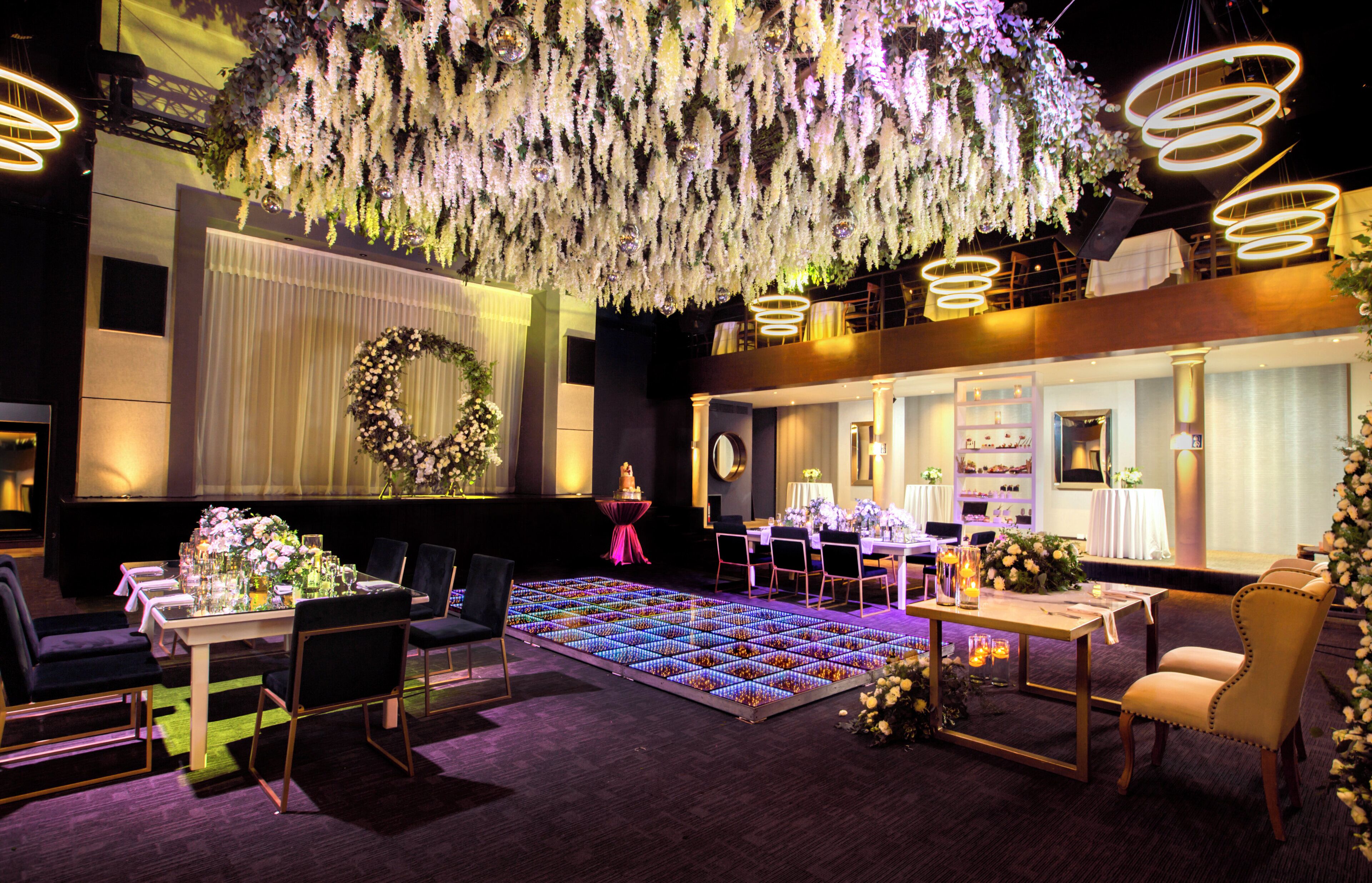 A hotel lobby with a reception desk, seating area, and a decorative floral arrangement.