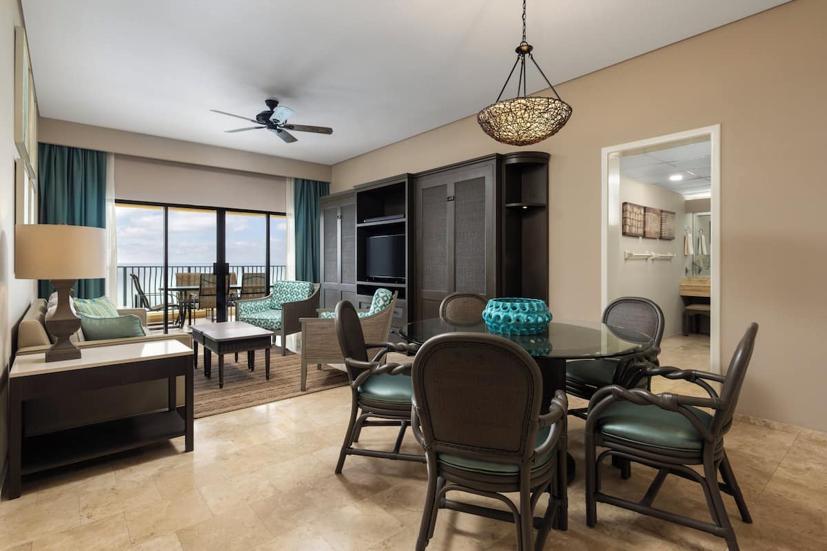 A dining area with a round table and chairs, a ceiling fan, and a view of the outdoors.