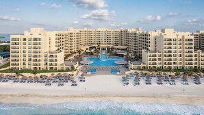 Un resort con piscina central, varios balcones y una zona de playa con tumbonas.