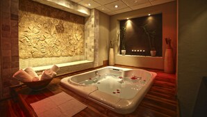 Un spa moderno con una bañera grande, una pared de piedra con un relieve y una ventana con una planta.