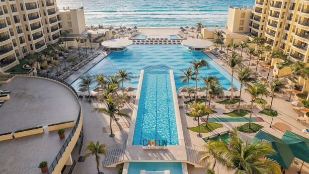 Un hotel con piscina central, acceso a la playa y vistas al océano.