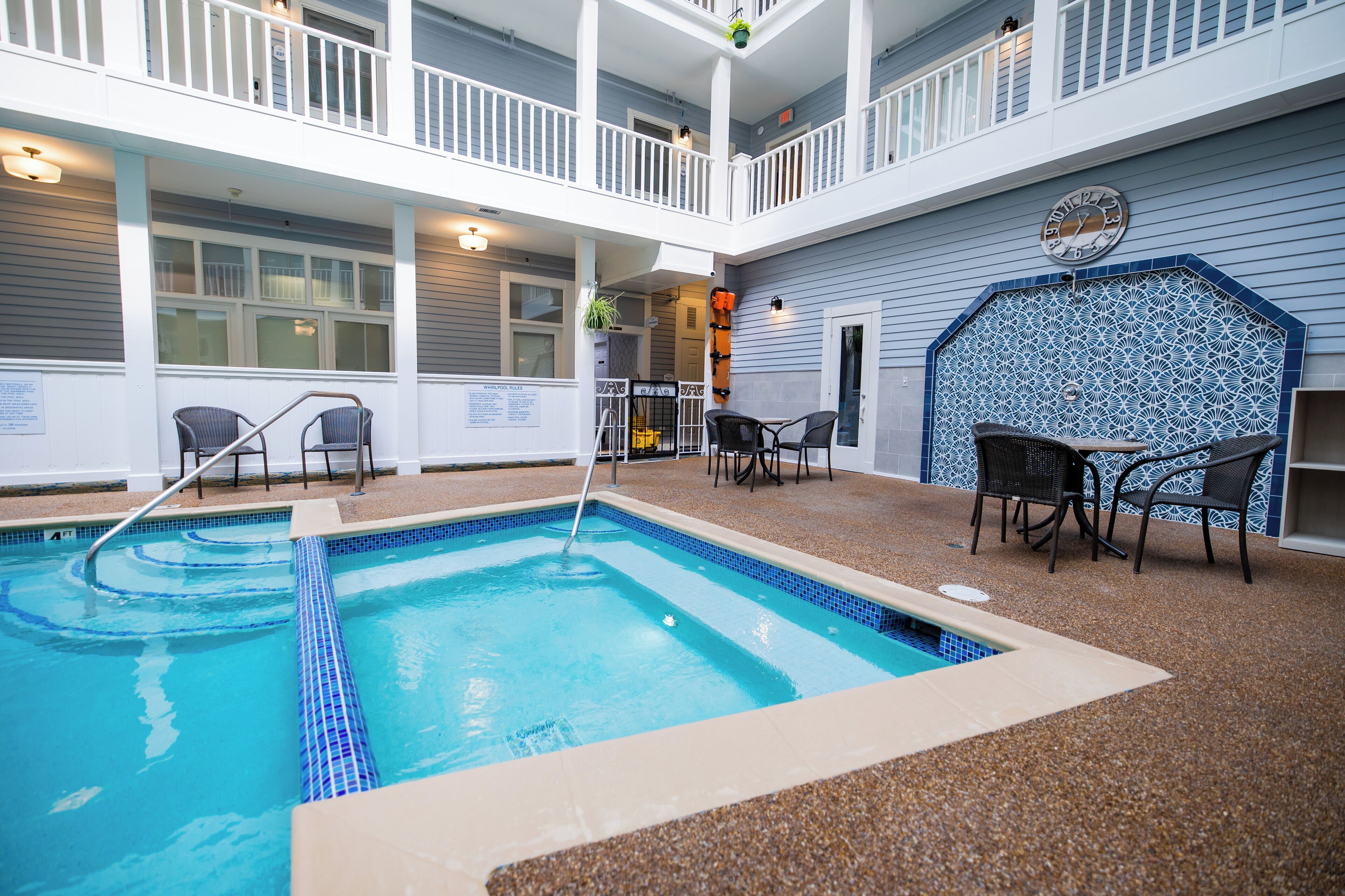 Un espace piscine doté d’une terrasse carrelée, de deux chaises longues et d’une petite table.