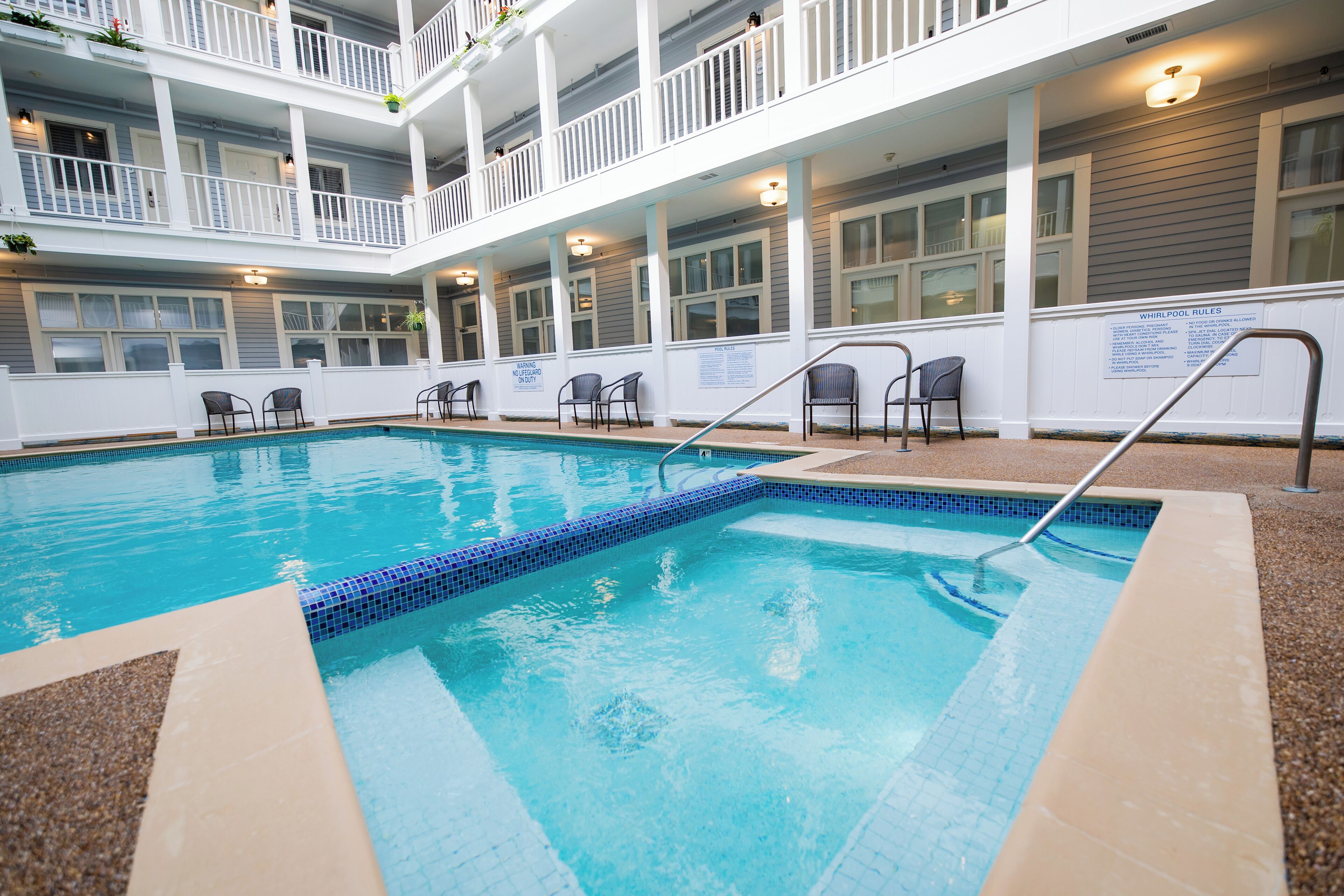 A pool area with a clear blue pool, white railings, and multiple levels of balconies.