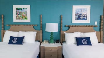 Habitación de hotel con dos camas, paredes verde azulado y obras de arte sobre cada cama.