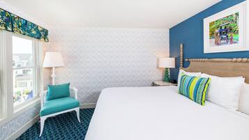 A hotel room with a large bed, a window with a view, a chair, and a painting on the wall.