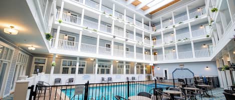 A multi-level indoor pool area with multiple balconies, seating areas, and a pool with a blue and white patterned floor.